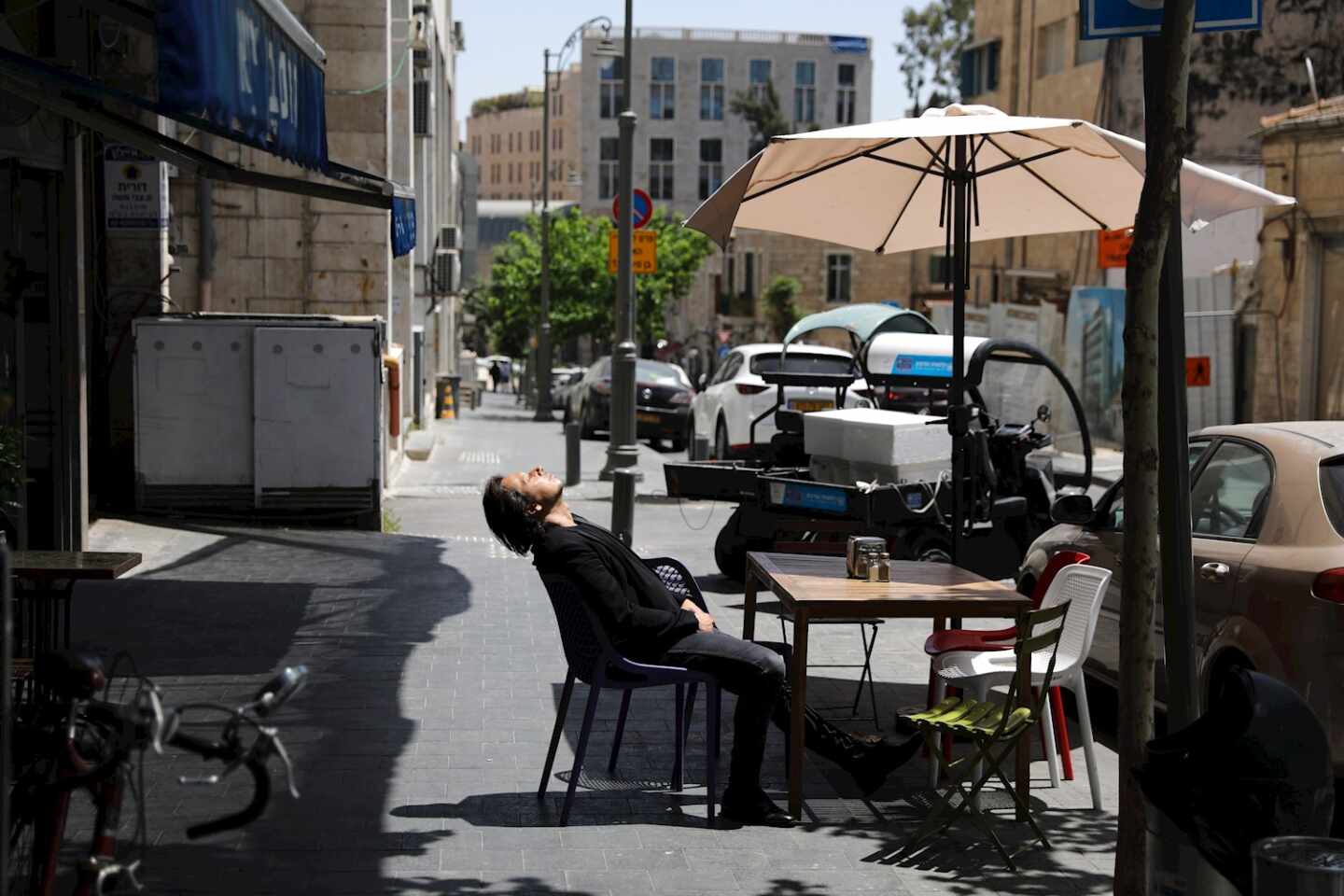 Un hombre sentado sin mascarilla en una terraza al aire libre en Jerusalén, días después de que el país eliminara el uso obligatorio de Mascarilla.