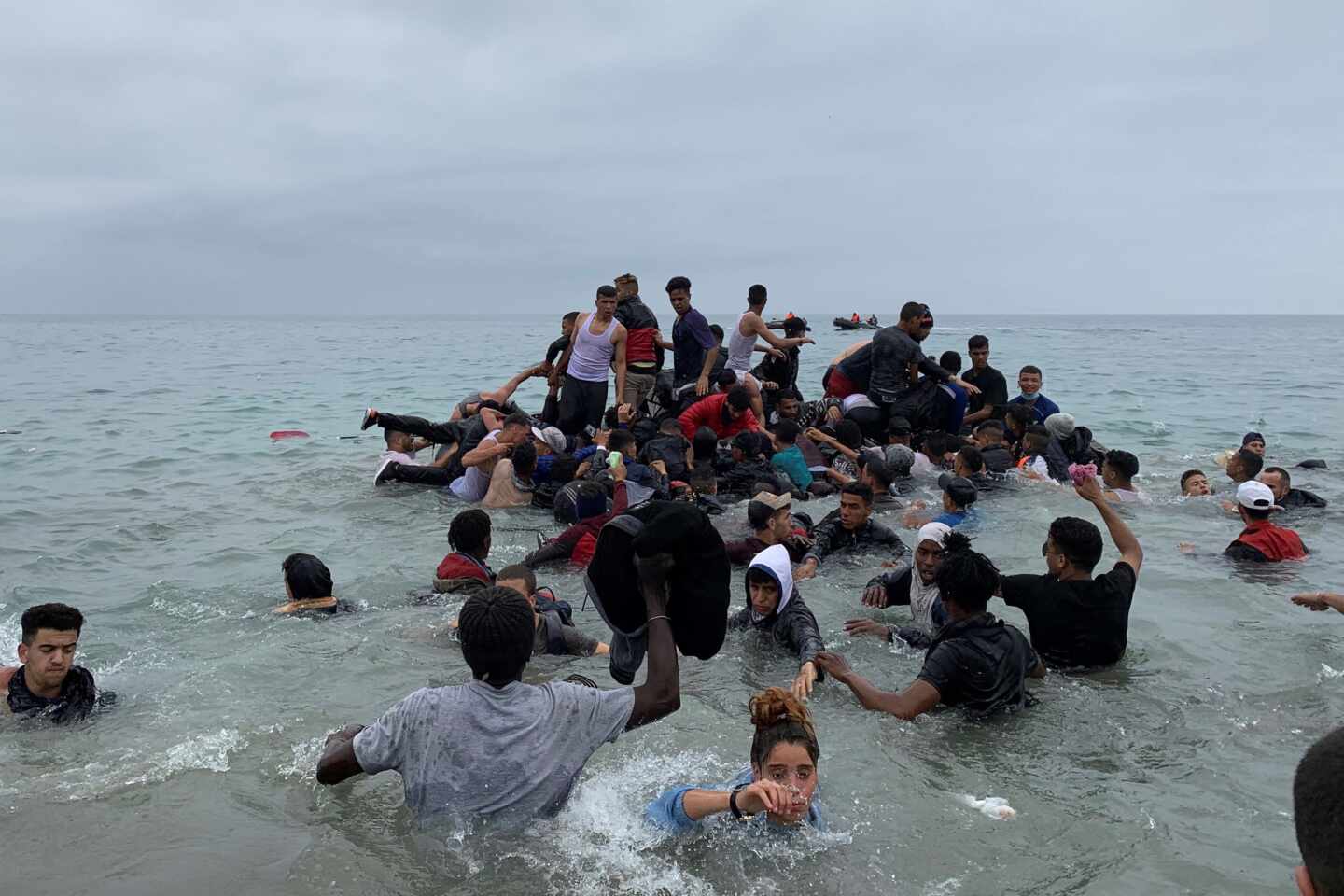 Un grupo de personas se hacen con una embarcación de las autoridades marroquíes en la playa de la localidad de Fnideq (Castillejos).