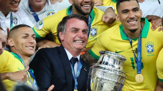 El inesperado gol geopolítico de Bolsonaro El presidente de Brasil, Jair Bolsonaro, sostiene la Copa América de 2019, rodeado de la selección nacional