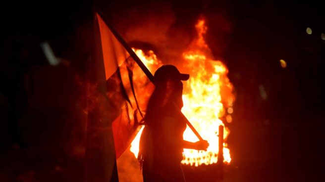 Unos manifestantes prenden fuego a unas llantas en una noche en Cali