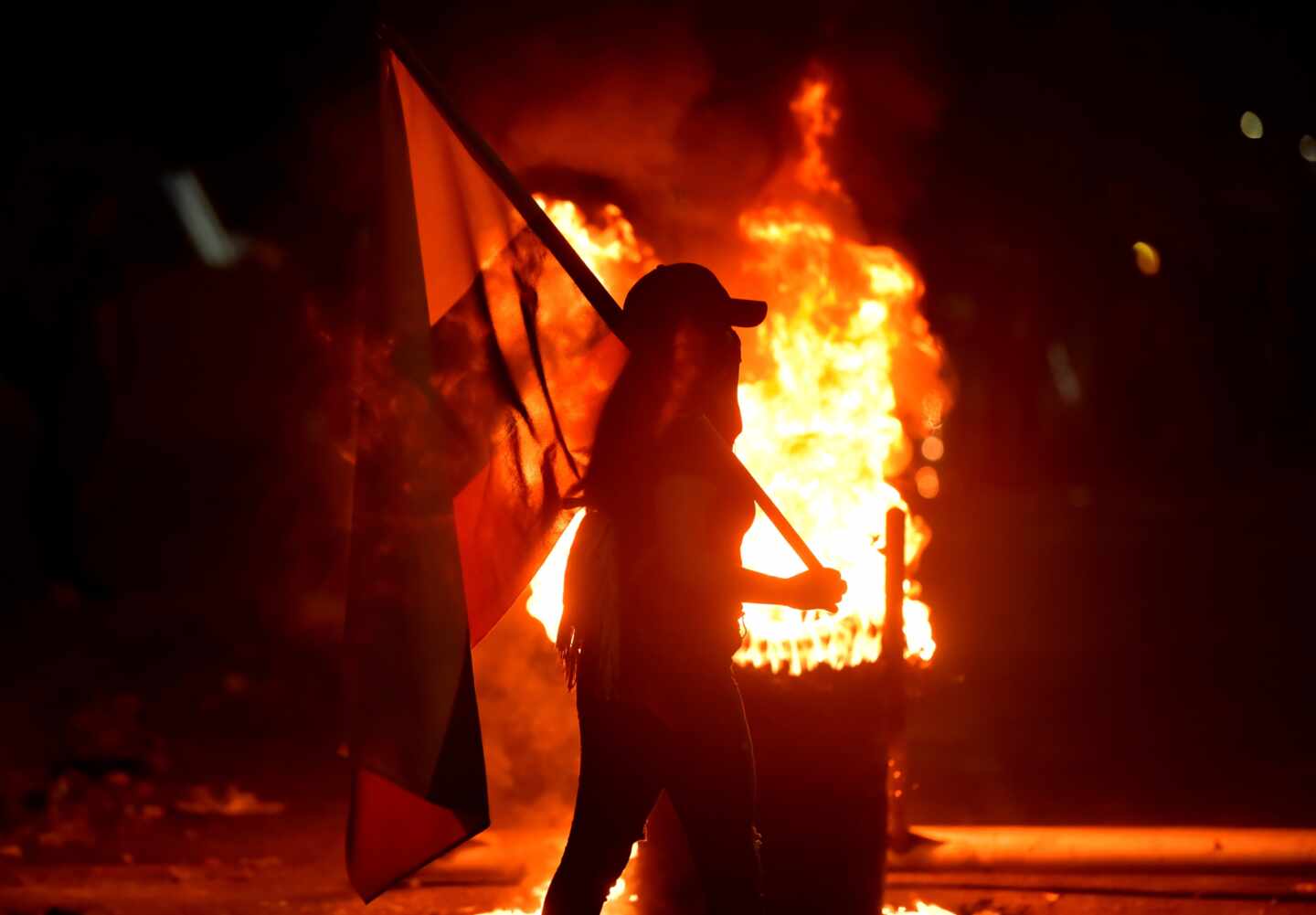 Unos manifestantes prenden fuego a unas llantas en una noche en Cali