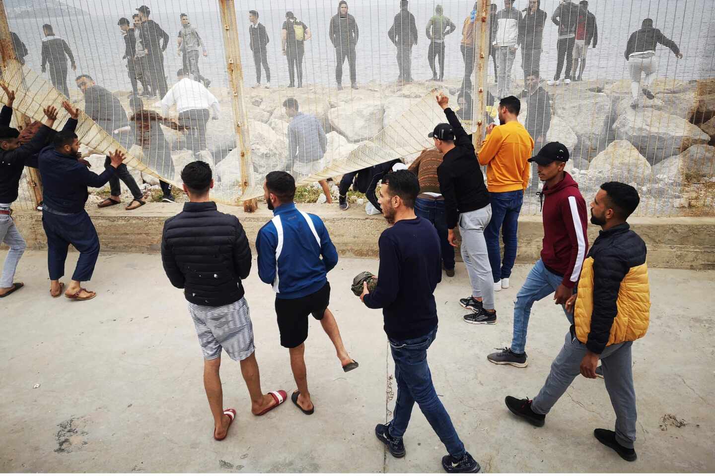 Un grupo de personas tratan de derribar la valla fronteriza en el lado marroquí