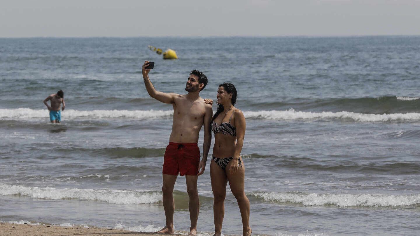 Dos personas se hacen un selfie en la Playa de la Malvarrosa.