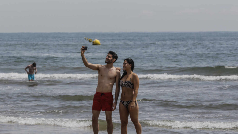 Dos personas se hacen un selfie en la Playa de la Malvarrosa.