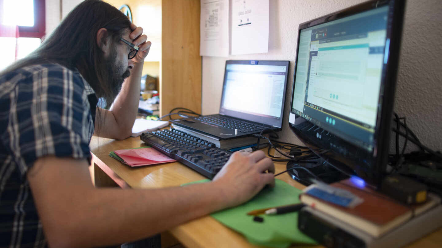 Un hombre teletrabaja, visiblemente cansado, desde su casa.