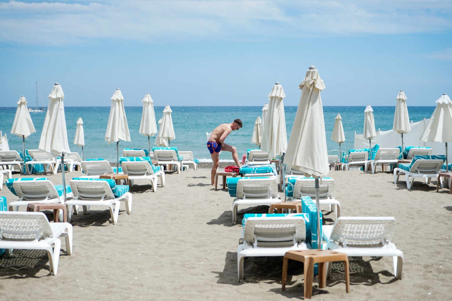 Un hombre se da crema en una playa vacía en Torremolinos, el primer día tras el estado de alarma.