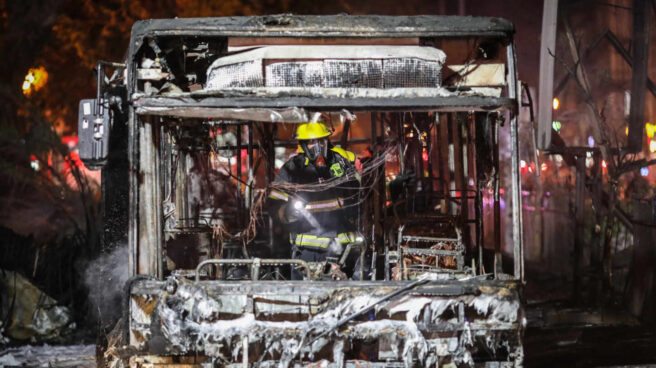 Un bombero israelí inspecciona un autobús quemado en Tel Aviv (Israel).