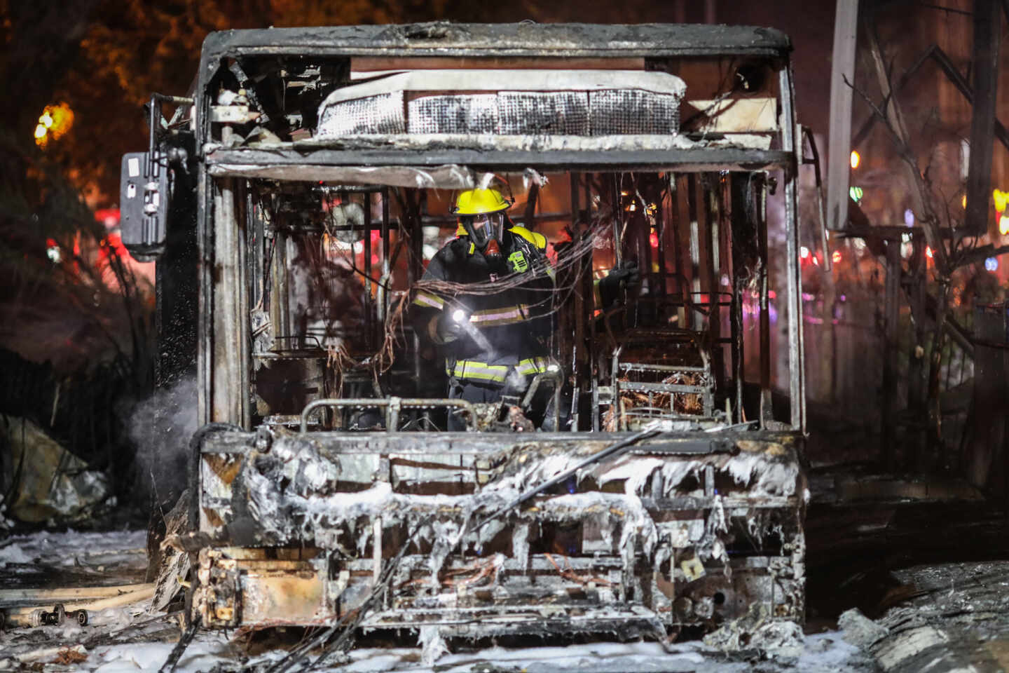 Un bombero israelí inspecciona un autobús quemado en Tel Aviv (Israel).