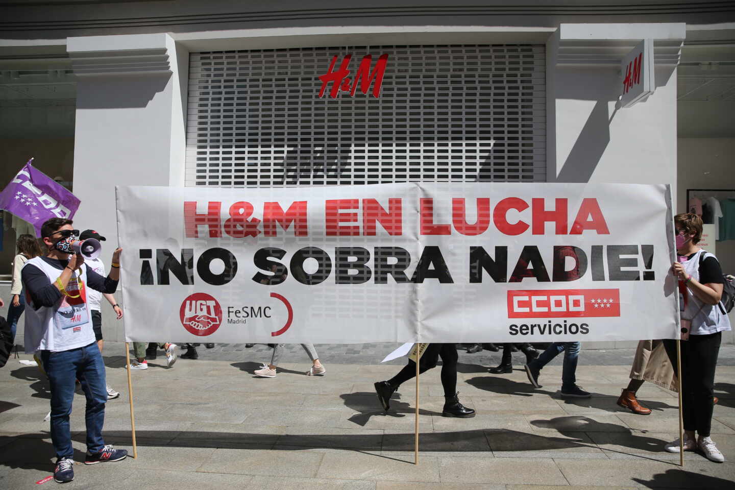 Varios trabajadores y trabajadoras de H&M se manifiestan frente a una tienda de la cadena.