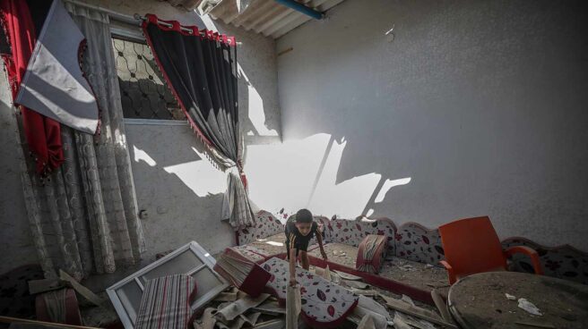 Un niño busca entre los escombros de su casa en Gaza
