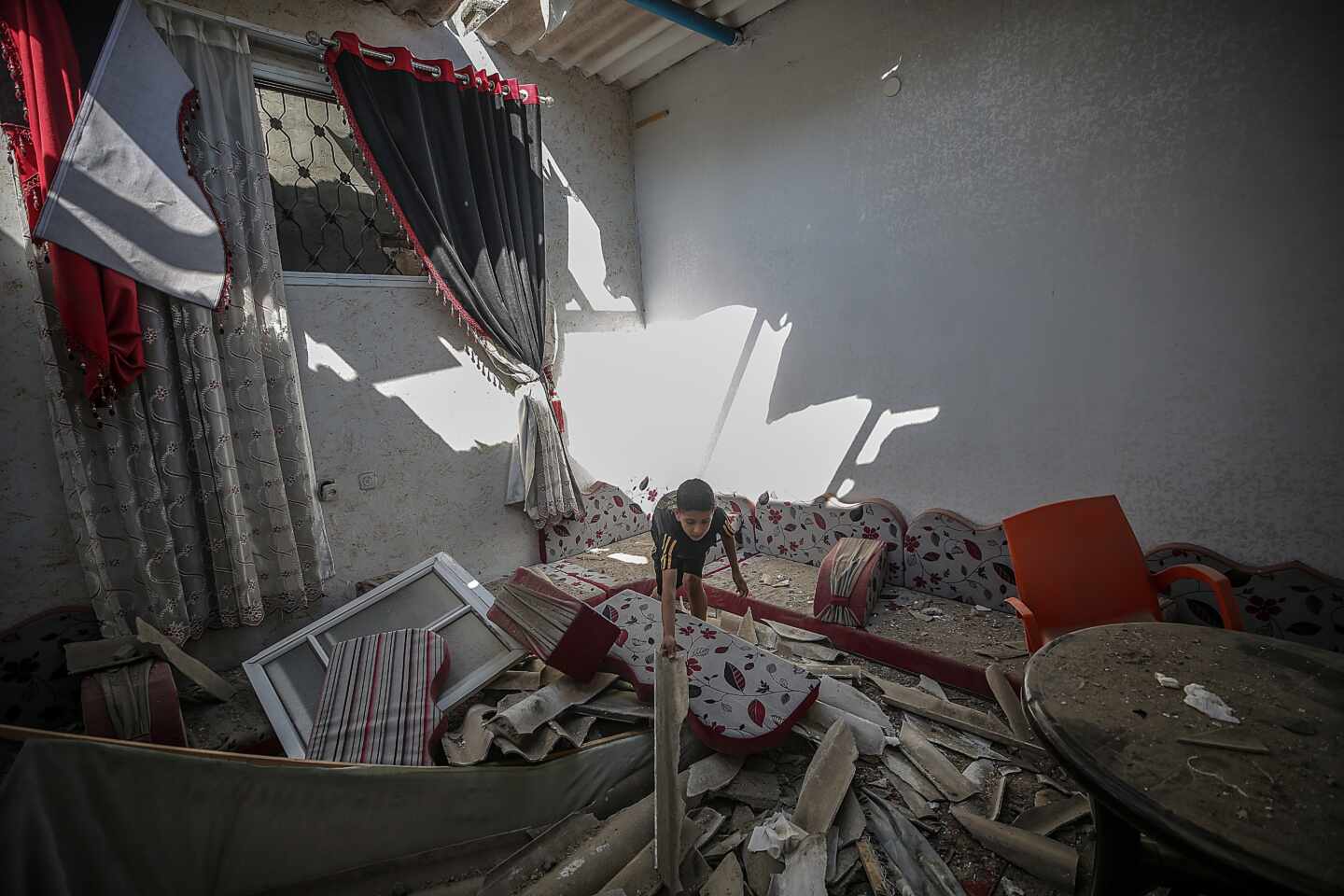 Un niño busca entre los escombros de su casa en Gaza