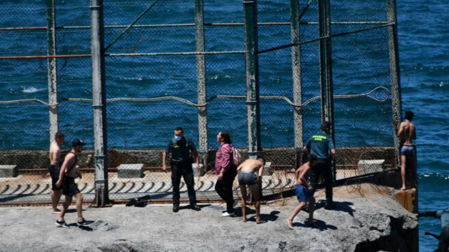 Guardias civiles junto a migrantes marroquíes que han llegado a nado este lunes a Ceuta.