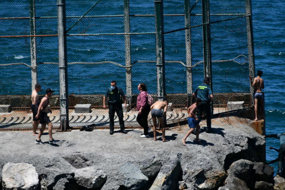 Guardias civiles junto a migrantes marroquíes que han llegado a nado este lunes a Ceuta.