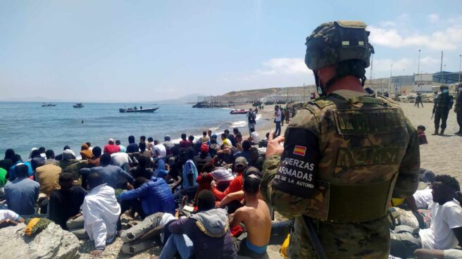 Un soldado del Ejército español vigila a numerosos inmigrantes en Ceuta