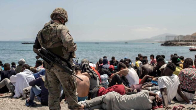 Un militar vigila a los inmigrantes en la playa de Ceuta.