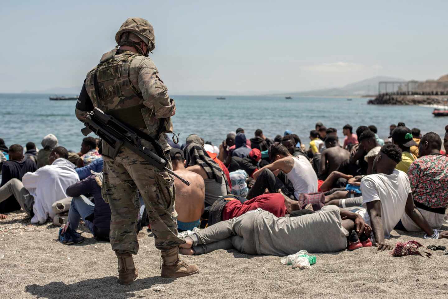 Un militar vigila a los inmigrantes en la playa de Ceuta.
