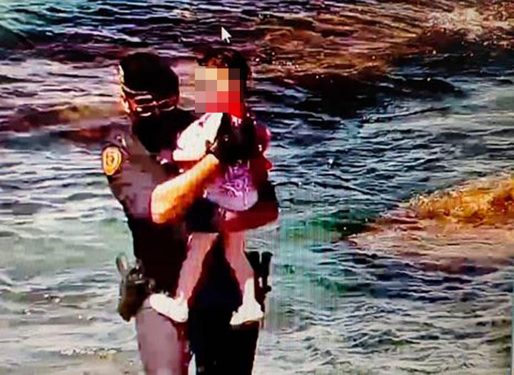Un Guardia Civil lleva a una niña en brazos tras sacarla del agua en Ceuta