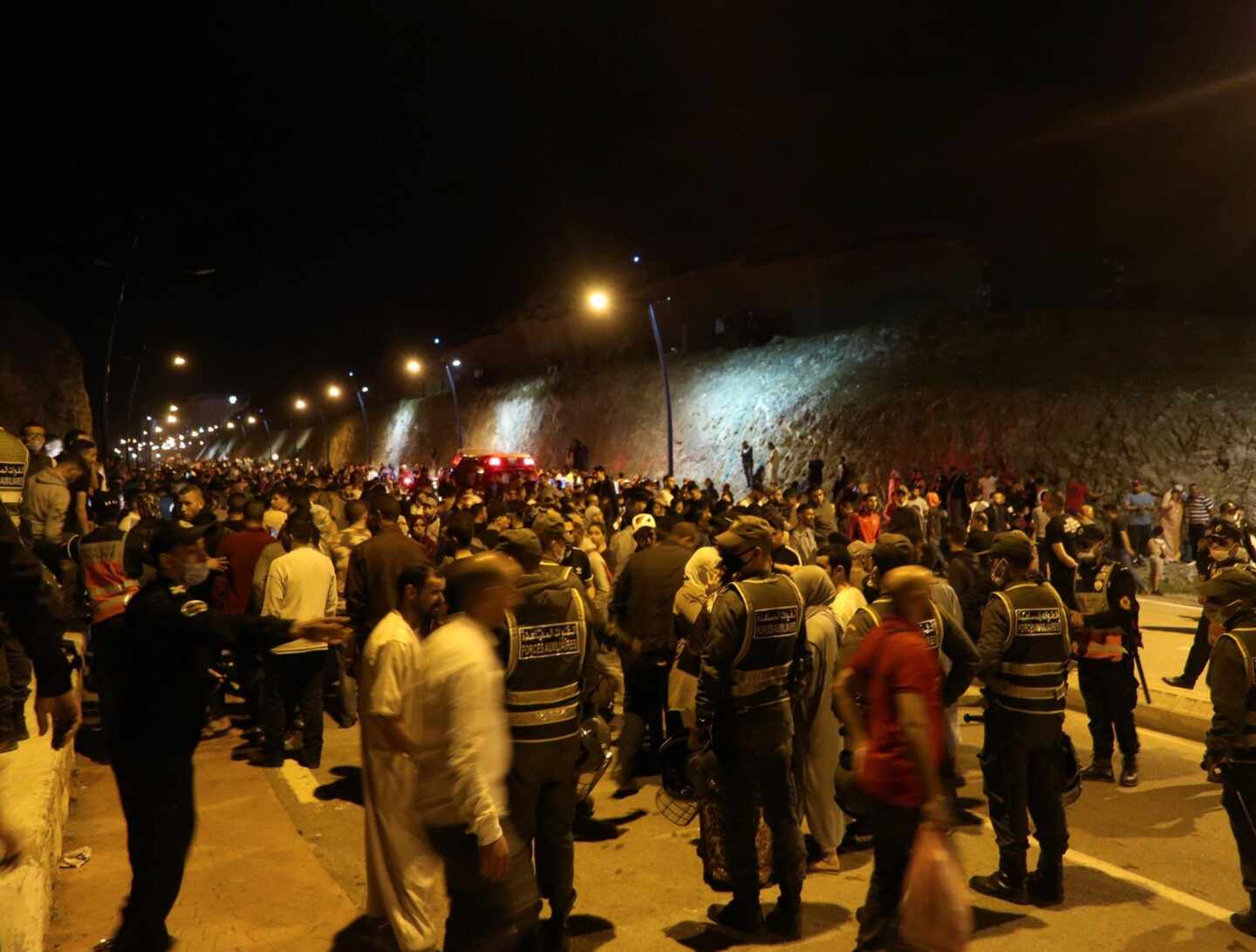 Jóvenes marroquíes esperan el momento de cruzar la frontera, por tierra o agua, este lunes en la localidad de Castillejos