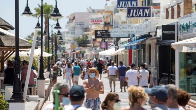 Varias personas disfrutan del buen tiempo paseando por el paseo marítimo de la playa de La Carihuela de Torremolinos