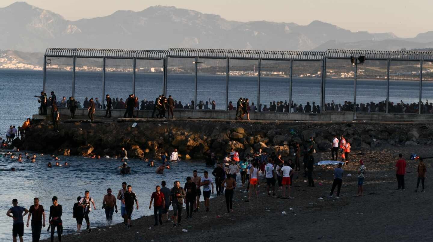 Migrantes marroquíes caminan por la playa del Tarajal, en Ceuta, el pasado lunes por la tarde.