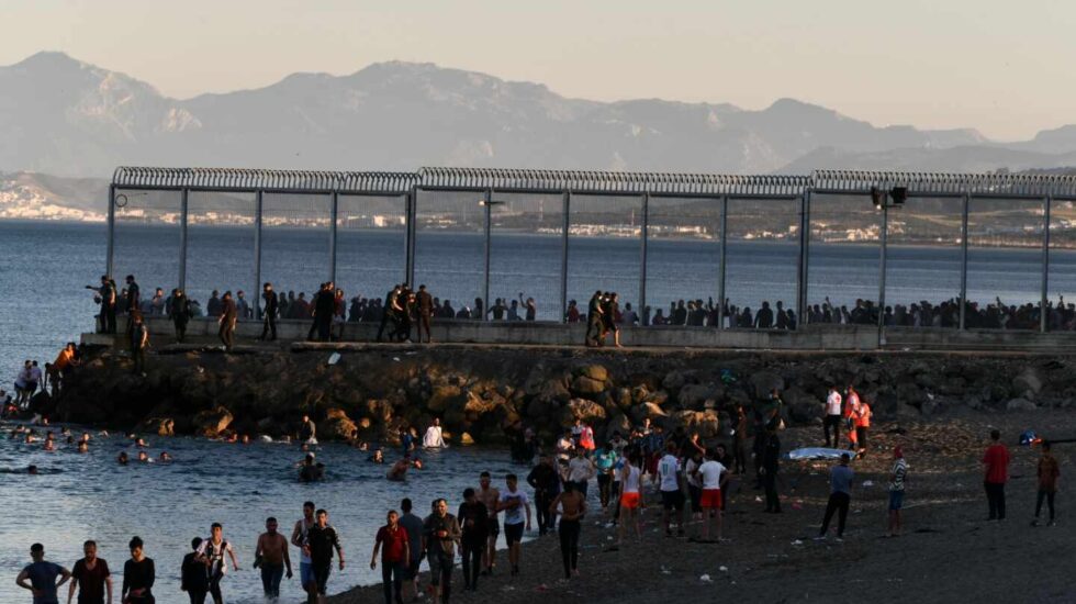 Migrantes marroquíes caminan por la playa del Tarajal, en Ceuta, el pasado lunes por la tarde.