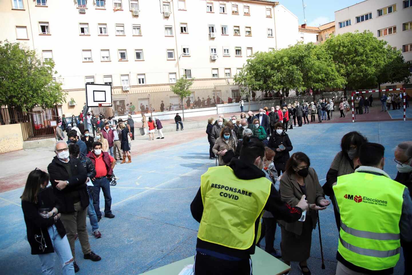 Cientos de personas hacen cola para votar en un colegio electoral de Madrid.