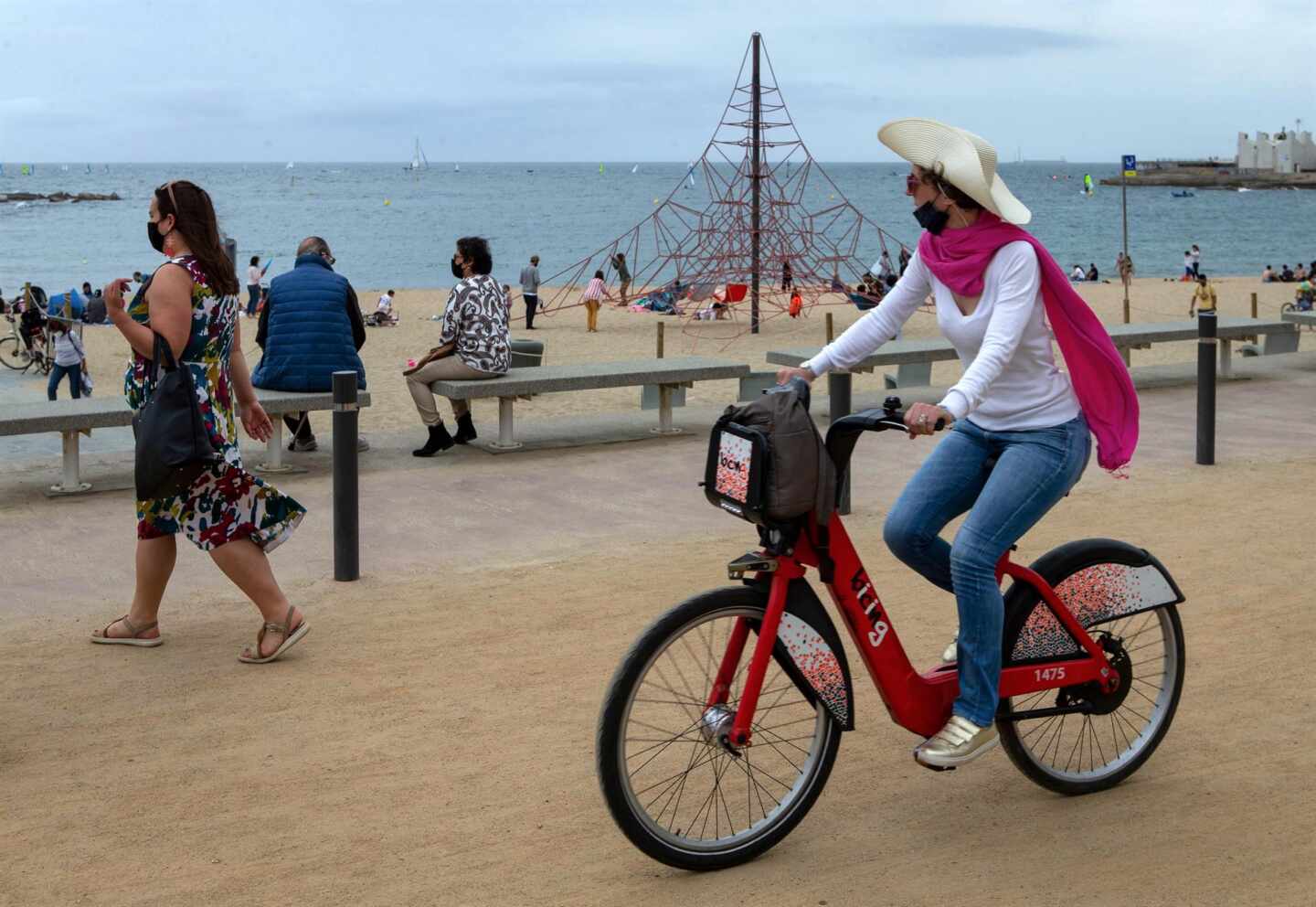 Una mujer pasea en bicicleta por la Barceloneta.