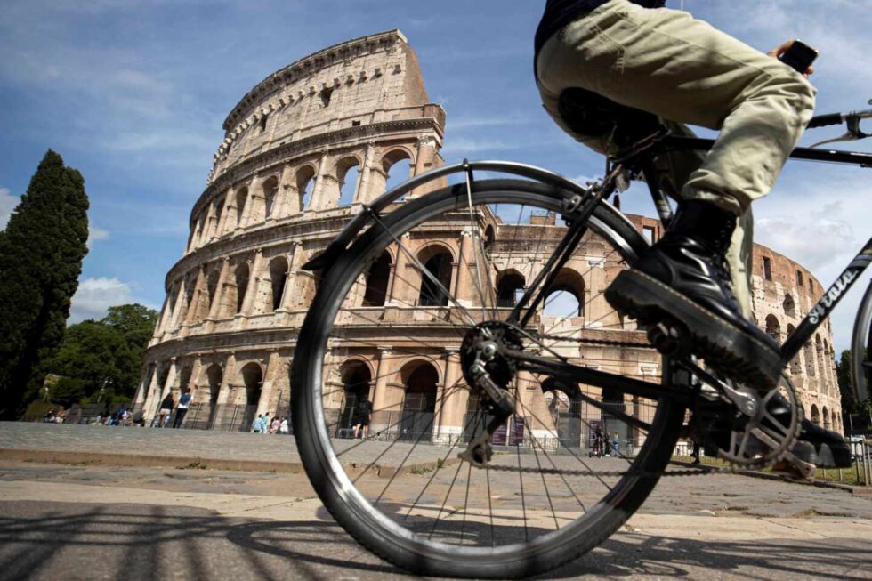 Una persona montada en bicicleta pasea junto al Coliseo de Roma, Italia.