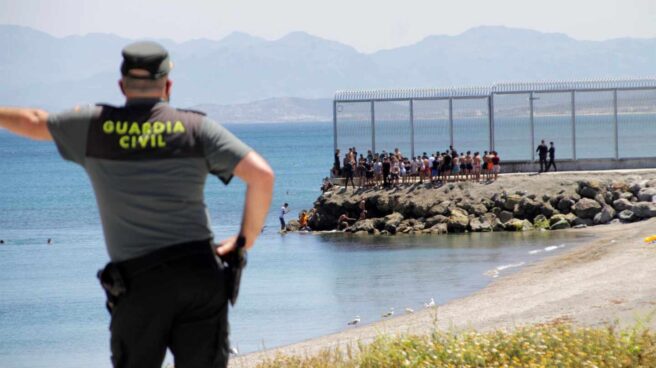 Un guardia civil contempla la llegada de marroquíes a Ceuta este lunes.