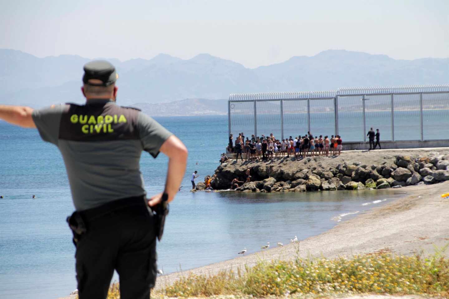 Un guardia civil contempla la llegada de marroquíes a Ceuta este lunes.