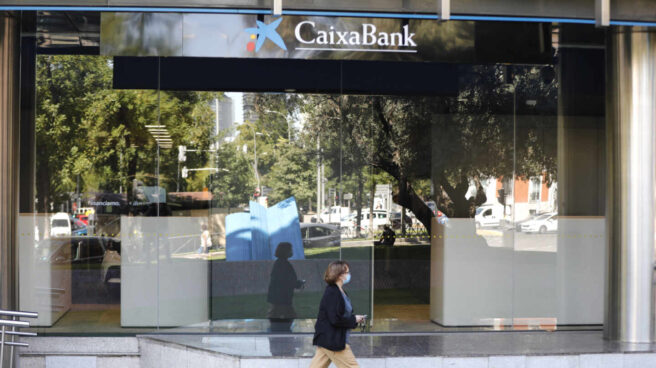 Un estudio señala que uno de cada cuatro trabajadores en planes de recolocación viene de la banca. Una mujer pasa por al lado de las oficinas de Caixabank en el Paseo Castellana, en Madrid (España)