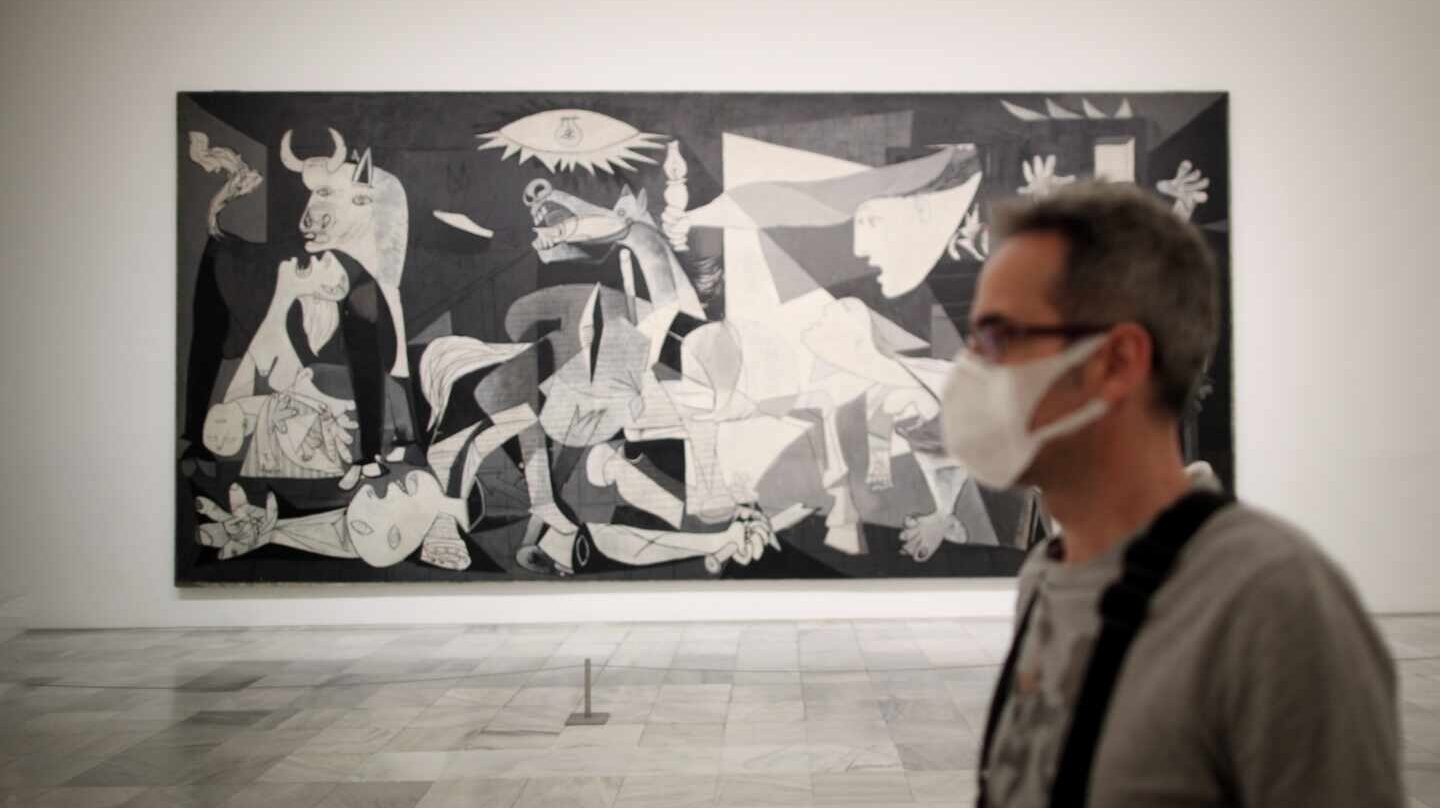 Un trabajador protegido con una mascarilla junto al cuadro de Pablo Picasso 'Guernica' en el Museo Nacional Centro de Arte Reina Sofía.
