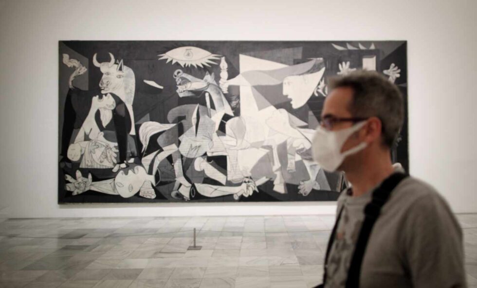 Un trabajador protegido con una mascarilla junto al cuadro de Pablo Picasso 'Guernica' en el Museo Nacional Centro de Arte Reina Sofía.