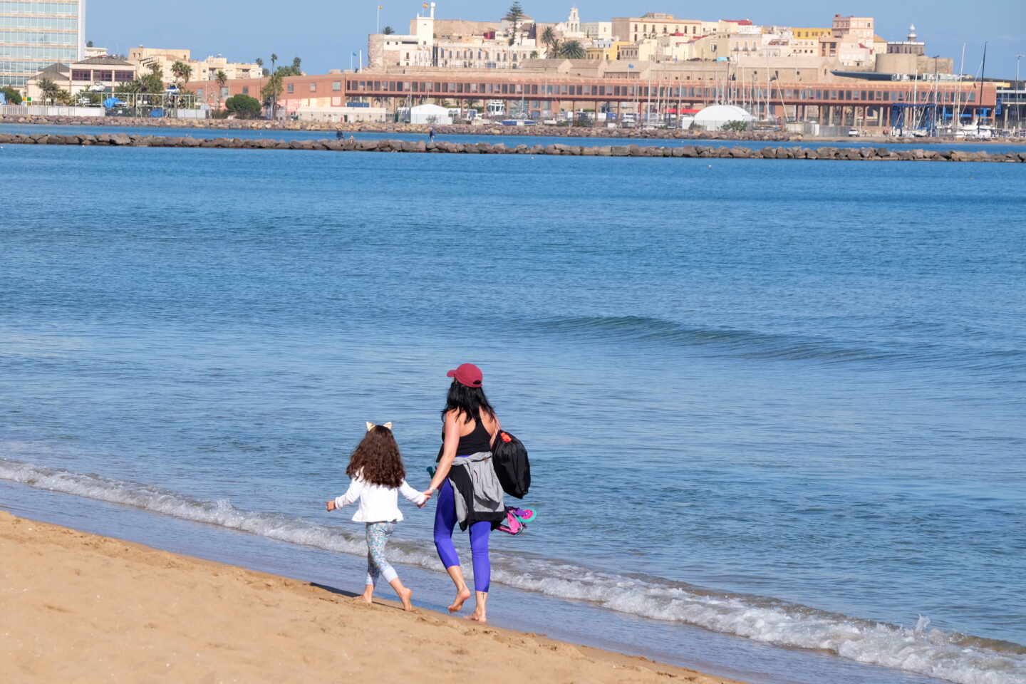 Una mujer y una niña pasean por la playa en Melilla.