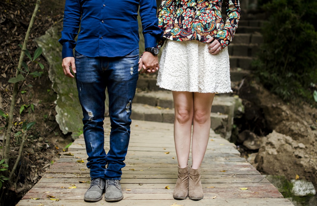 Una pareja de la mano a la que se ve de torso para abajo.