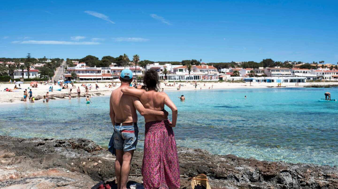 Una pareja observa la playa de Punta Prima en Menorca