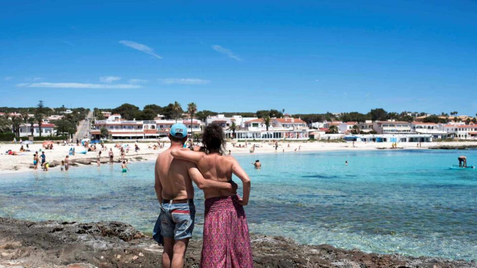 Una pareja observa la playa de Punta Prima en Menorca