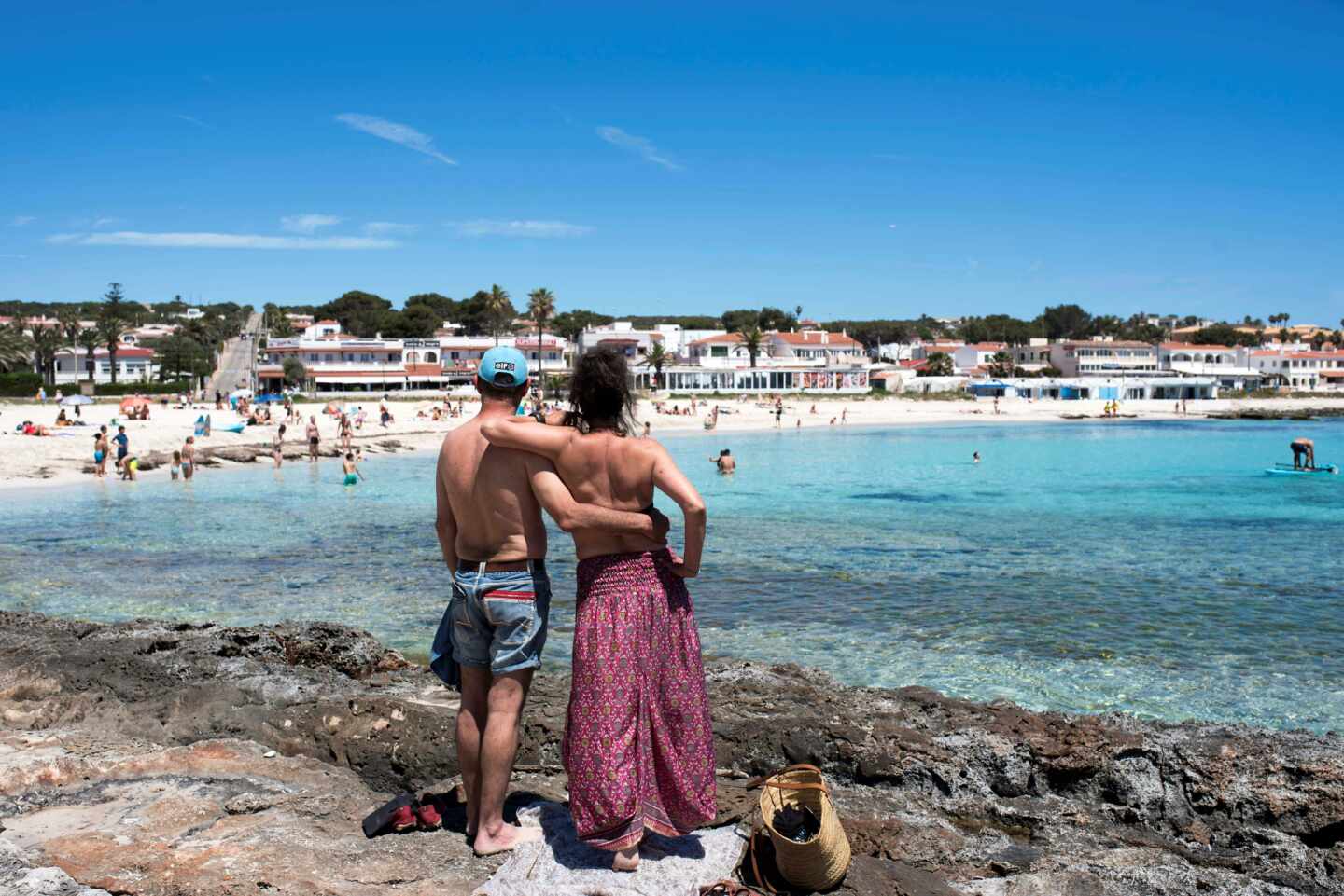 Una pareja observa la playa de Punta Prima en Menorca