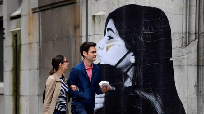 Primer día sin mascarillas, en imágenes Dos personas caminan con la mascarilla en la mano ante la puerta de entrada de ambulancias del Hospital de la Cruz Roja, este sábado en Oviedo.