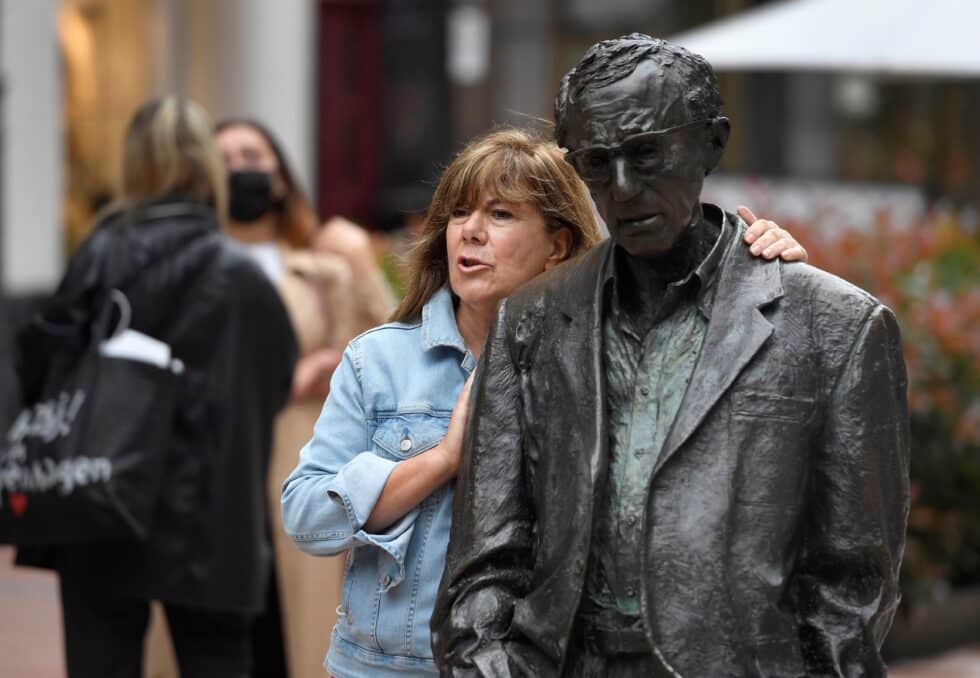 Una mujer sin mascarilla se toma un fotrografía junto a la estatua del cineasta estadounidense Woody Allen.