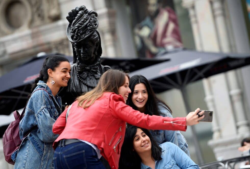 Turistas sin mascarilla se toman una fotografía junto a la estatua de la Regenta de "Clarín", este sábado en Oviedo.