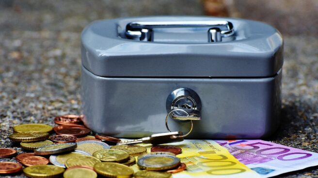 Los españoles ahorraron en el primer trimestre un 165% más que el año pasado Monedas y billetes junto a un cofre