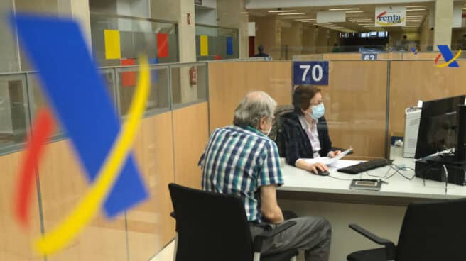 La Agencia Tributaria comienza a atender presencialmente para hacer la declaración en sus oficinas Un hombre haciendo la declaración de la renta con una empleada de la Agencia Tributaria