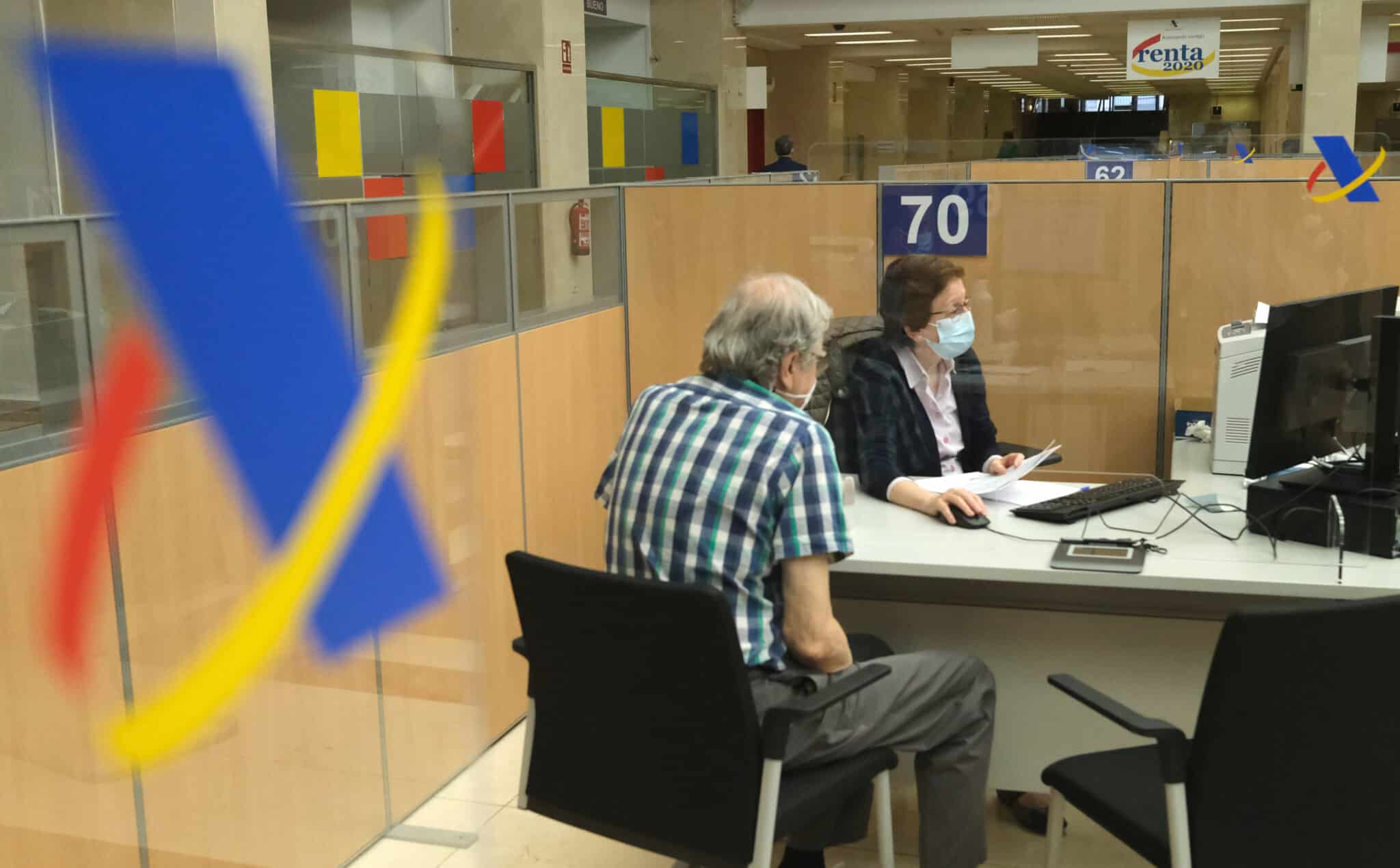 Un hombre haciendo la declaración de la renta con una empleada de la Agencia Tributaria