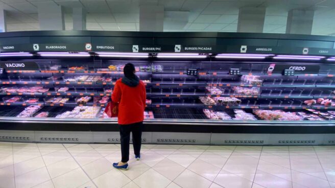 Una mujer observa los alimentos que quedan en los refrigeradores de carne de un supermercado un día marcado por colas de gente deseosas de hacer acopio de alimentos y otros productos debido al avance del coronavirus.