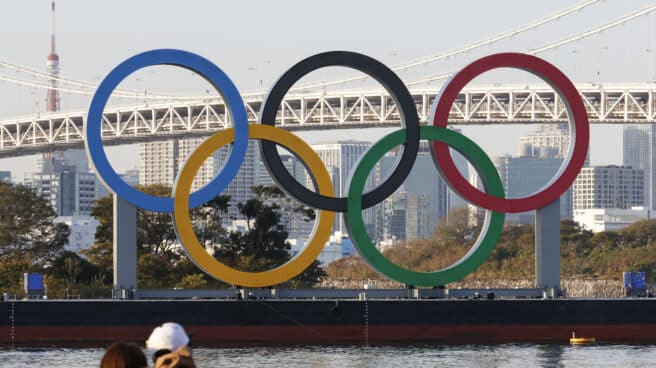 Una pareja observa los anillos olímpicos en un puente de Tokio