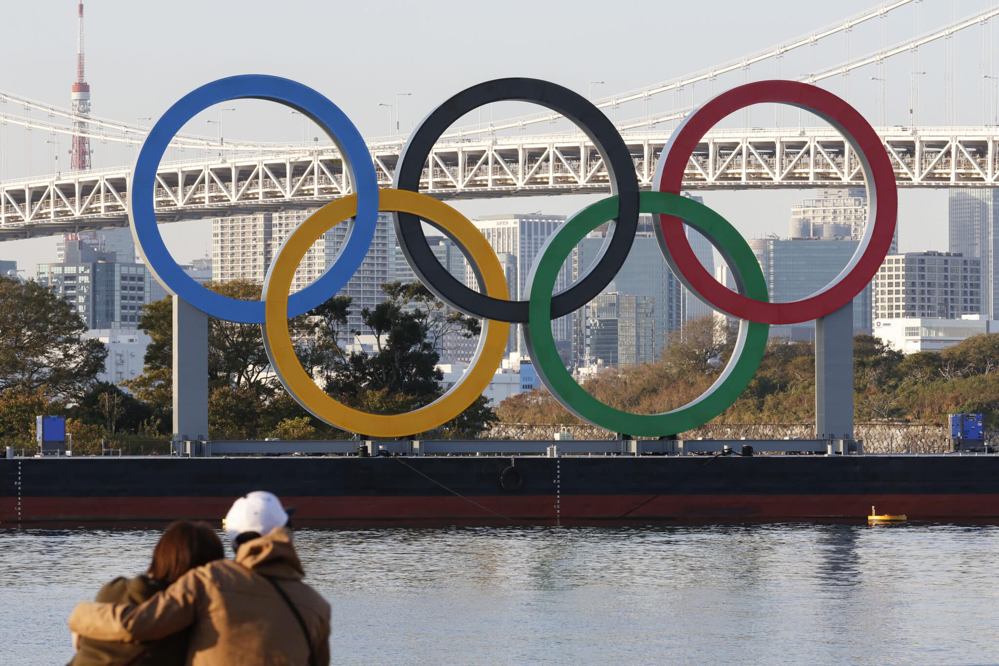 Una pareja observa los anillos olímpicos en un puente de Tokio