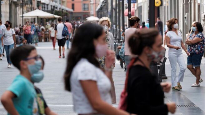 Personas paseando por la calle utilizando la mascarilla