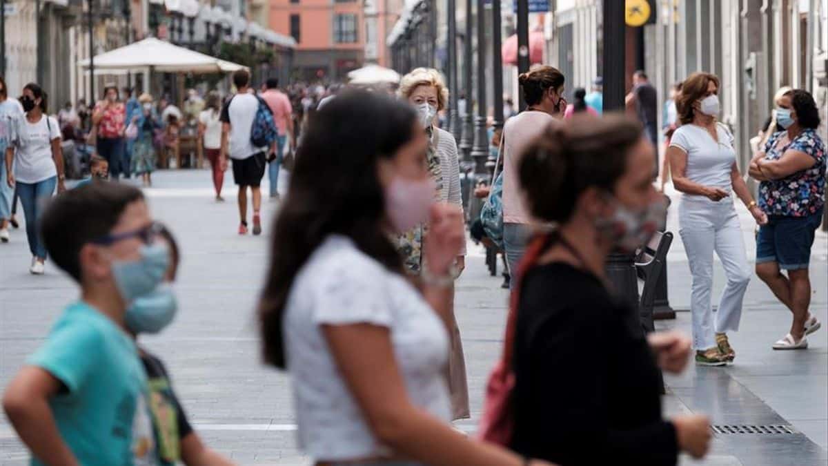 Personas paseando por la calle utilizando la mascarilla