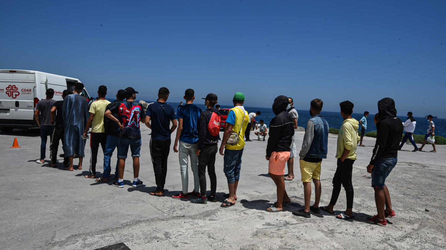 Migrantes hacen cola ante una furgoneta de Cáritas para recoger bolsas de comida en Ceuta.